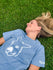 Person wearing a blue t-shirt with a donkey graphic lying on grass
